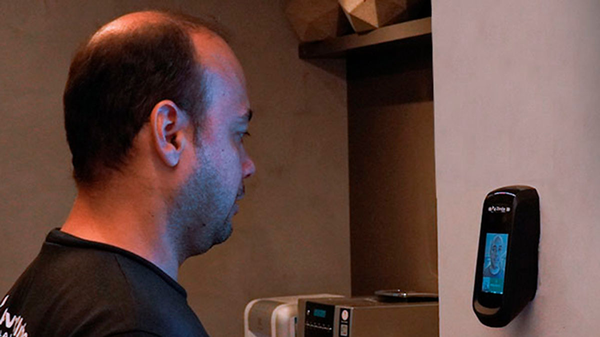 Um funcionário registrando o ponto em um leitor facial.