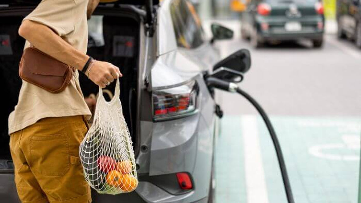 homem faz compras enquanto usa o carregador no carro elétrico.